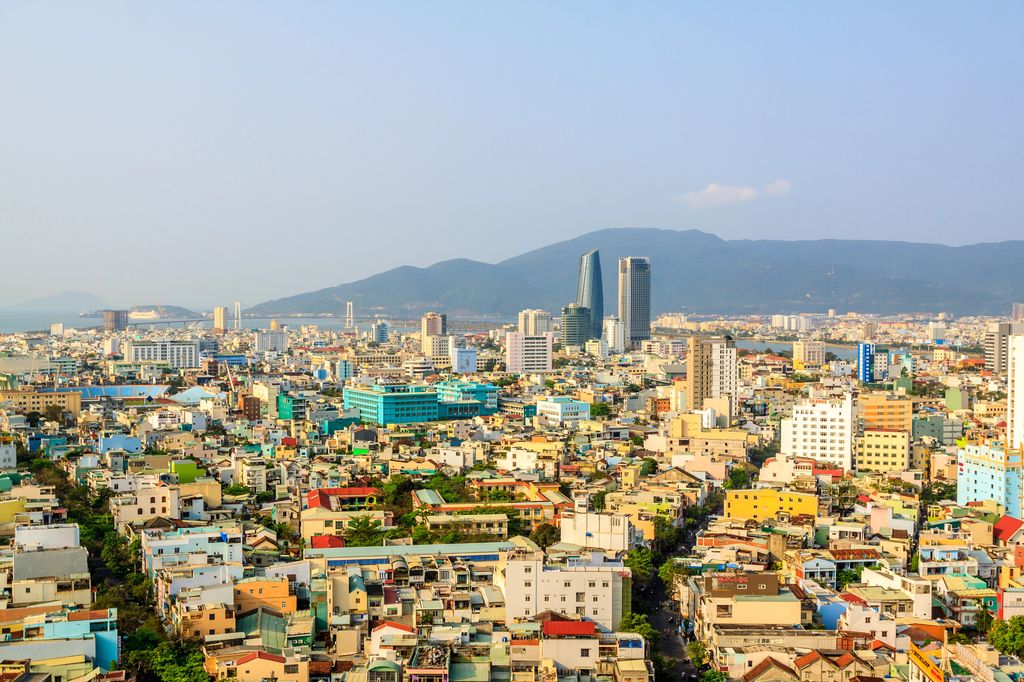 The city of Da Nang, Vietnam full of buildings and with a view of the mountains in the background.