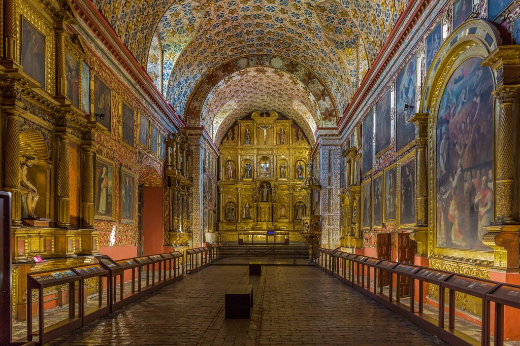 The interior of Museo Iglesia de Santa Clara in Bogota, Colombia, adorned with paintings, statues, and wall and ceiling art. 